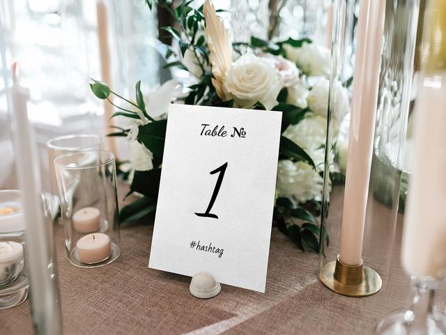 Verfraai je tafeldecoratie met deze elegante tafelnummerdisplay, omringd door weelderige bloemen en gloeiende kaarsen. Deze chique opstelling is perfect voor bruiloften of chique evenementen en helpt gasten hun plaats te vinden terwijl het een vleugje verfijning toevoegt aan de sfeer van je evenement.