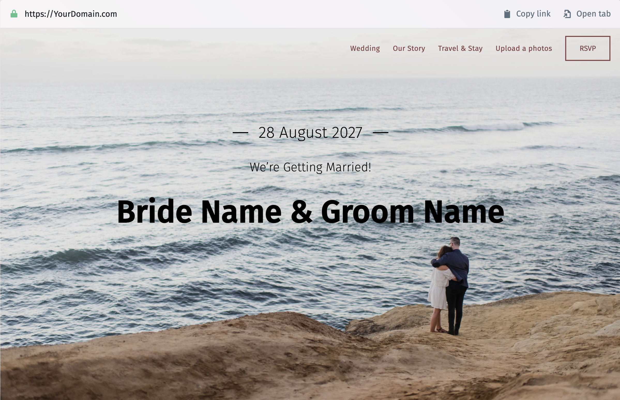 Screenshot della homepage di un sito web di nozze che mostra una coppia abbracciata su una scogliera di fronte all’oceano. Il testo riporta “28 Agosto”, “Ci sposiamo!” e “Nome Sposa & Nome Sposo”. Nel menu in alto compaiono le voci “Matrimonio”, “La nostra storia”, “Viaggio & Soggiorno”, “Carica una foto” e “Invito”. In alto a sinistra si vede il nome di dominio, con i pulsanti per copiare il link e aprire in una nuova scheda.