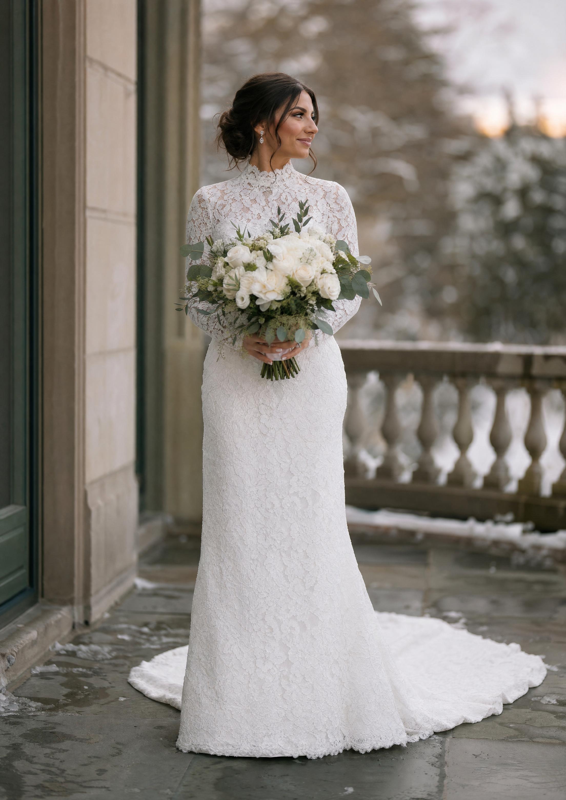 Núvia amb un vestit de núvia de màniga llarga de punta per tot arreu i coll alt, un look elegant i atemporal per a un casament d’hivern