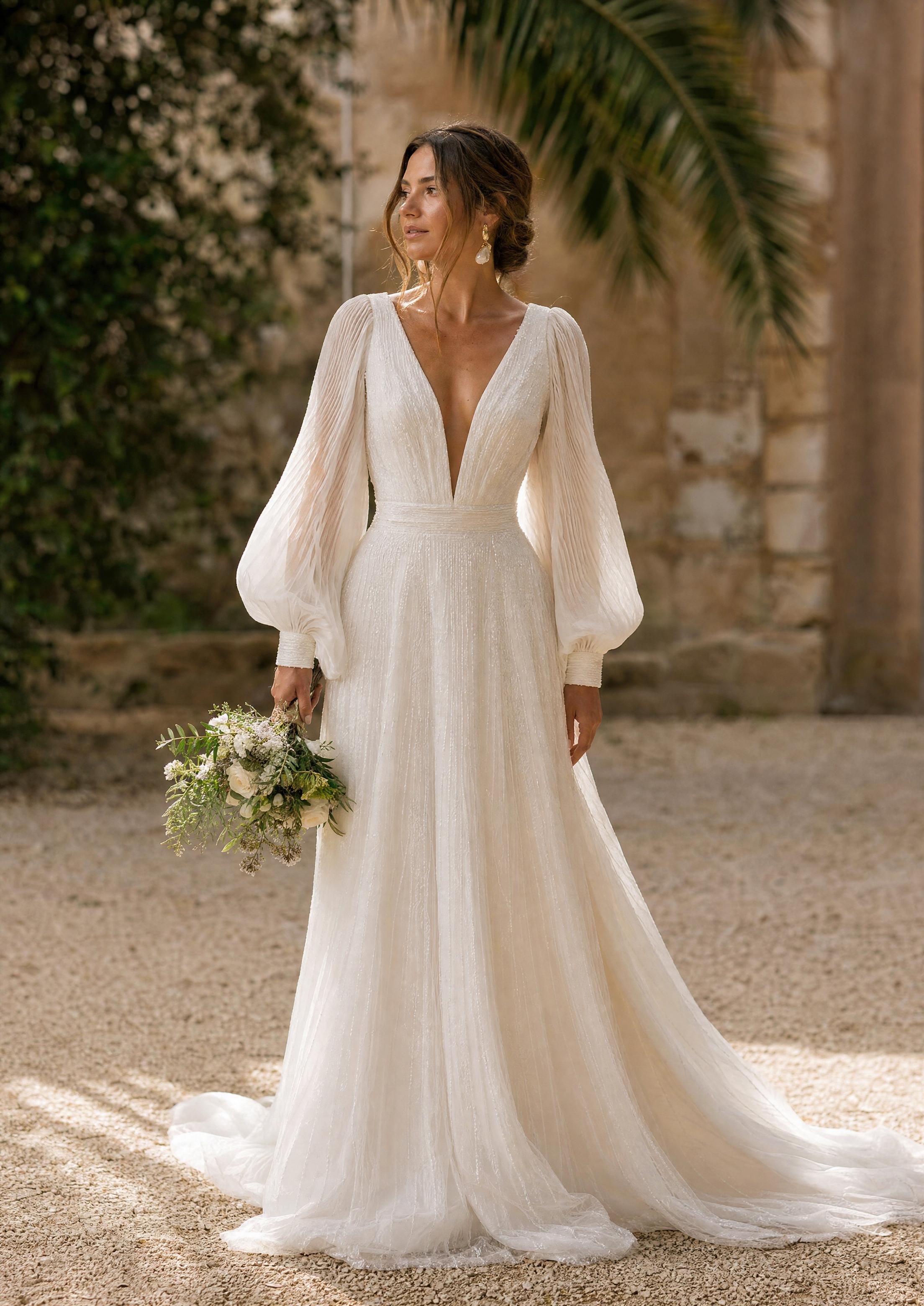 Núvia amb un vestit de núvia amb espectaculars mànigues bisbe voluminoses recollides en punys nets, un look boho amb personalitat