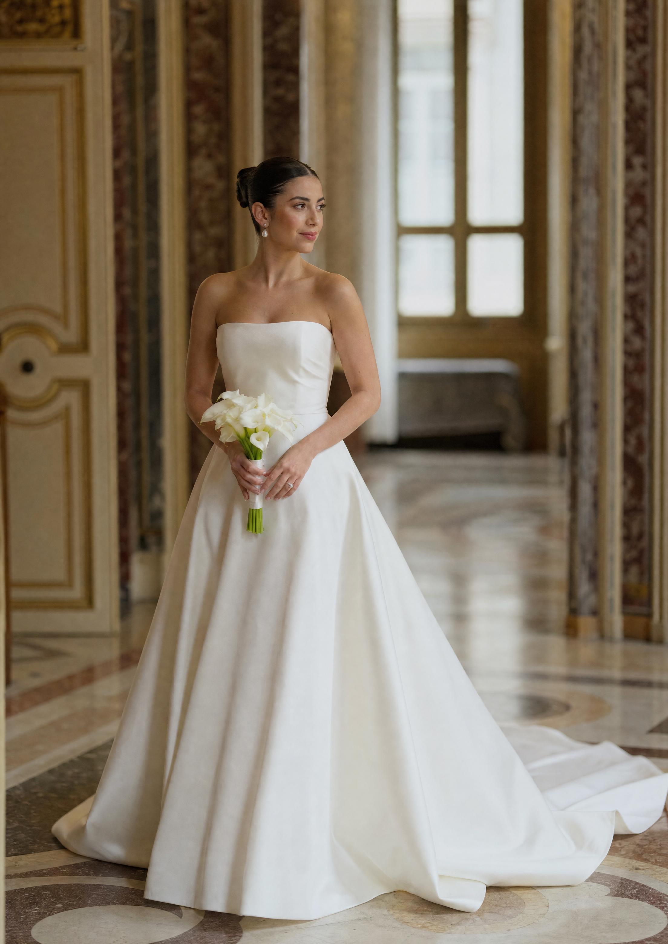 Núvia amb un elegant vestit de núvia de setí amb una lluentor natural, amb el teixit caient amb elegància sobre una silueta fluida