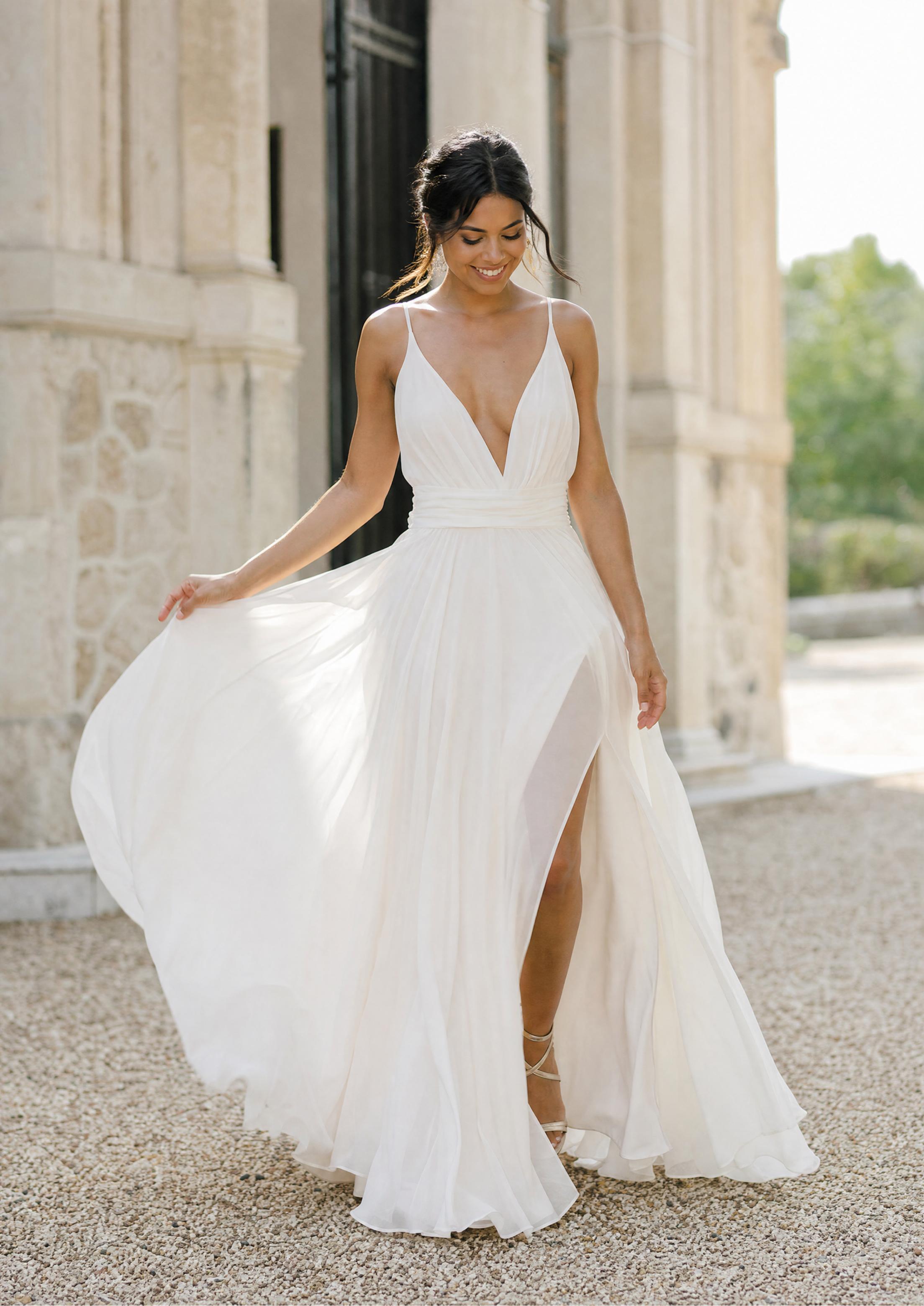 Bride in a sheer chiffon summer wedding dress, the lightweight fabric floating as she walks through soft sunlight