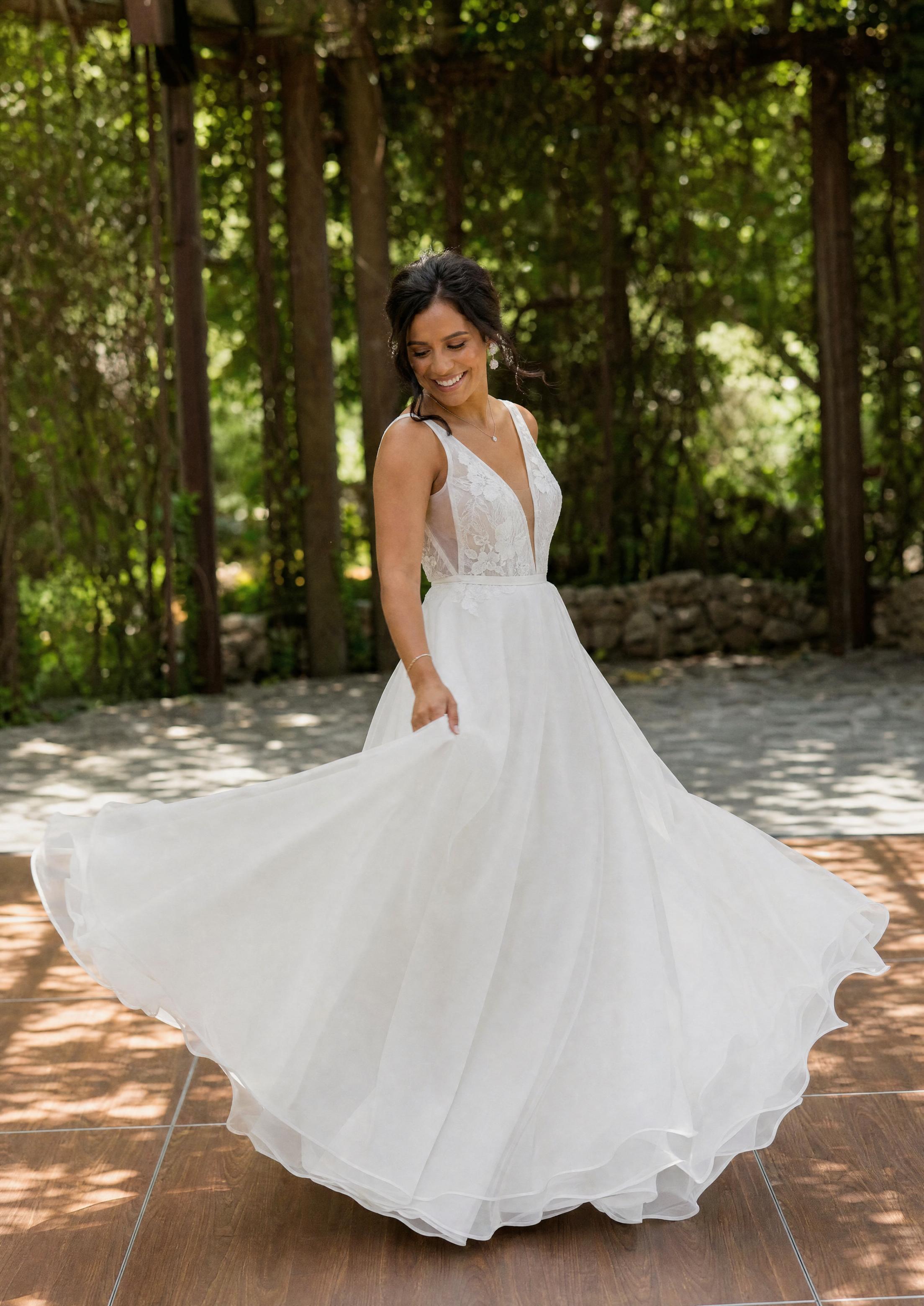 Bride in a flowing A-line organza summer wedding dress twirling on an open-air dance floor, skirt catching the light